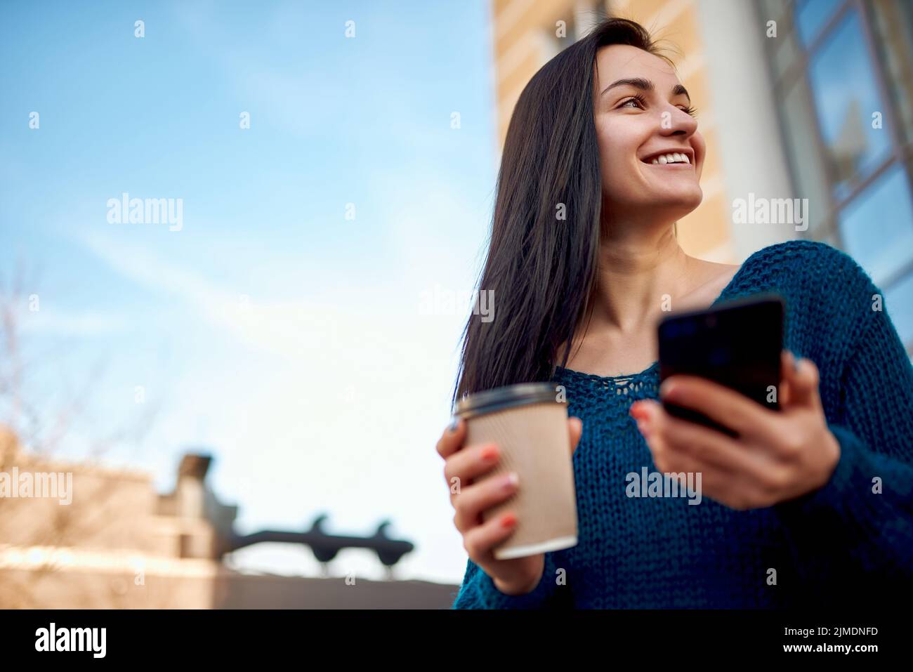 Angenehme Studentin, die sich an einem schönen sonnigen Tag auf einem Stadtspaziergang entspannt Stockfoto