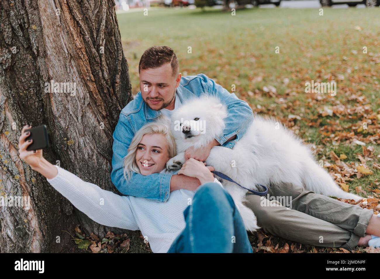 Glückliches junges Paar mit Hund, der Spaß im Park hat Stockfoto