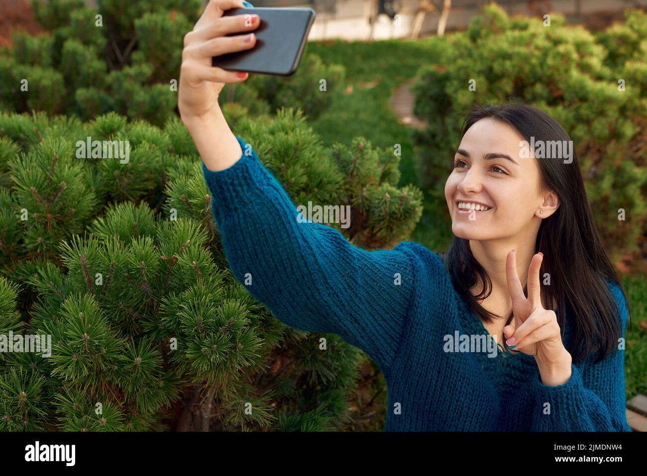 Lady macht Selfie auf einer Handykamera in einem malerischen Hof Stockfoto