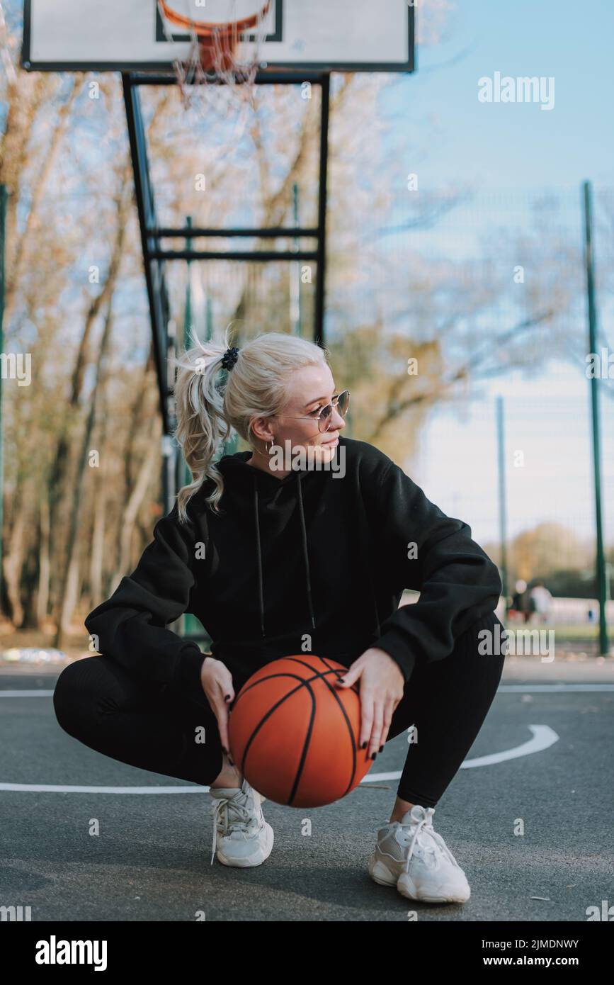 Die hübsche Dame hocke auf einem Basketballplatz Stockfoto