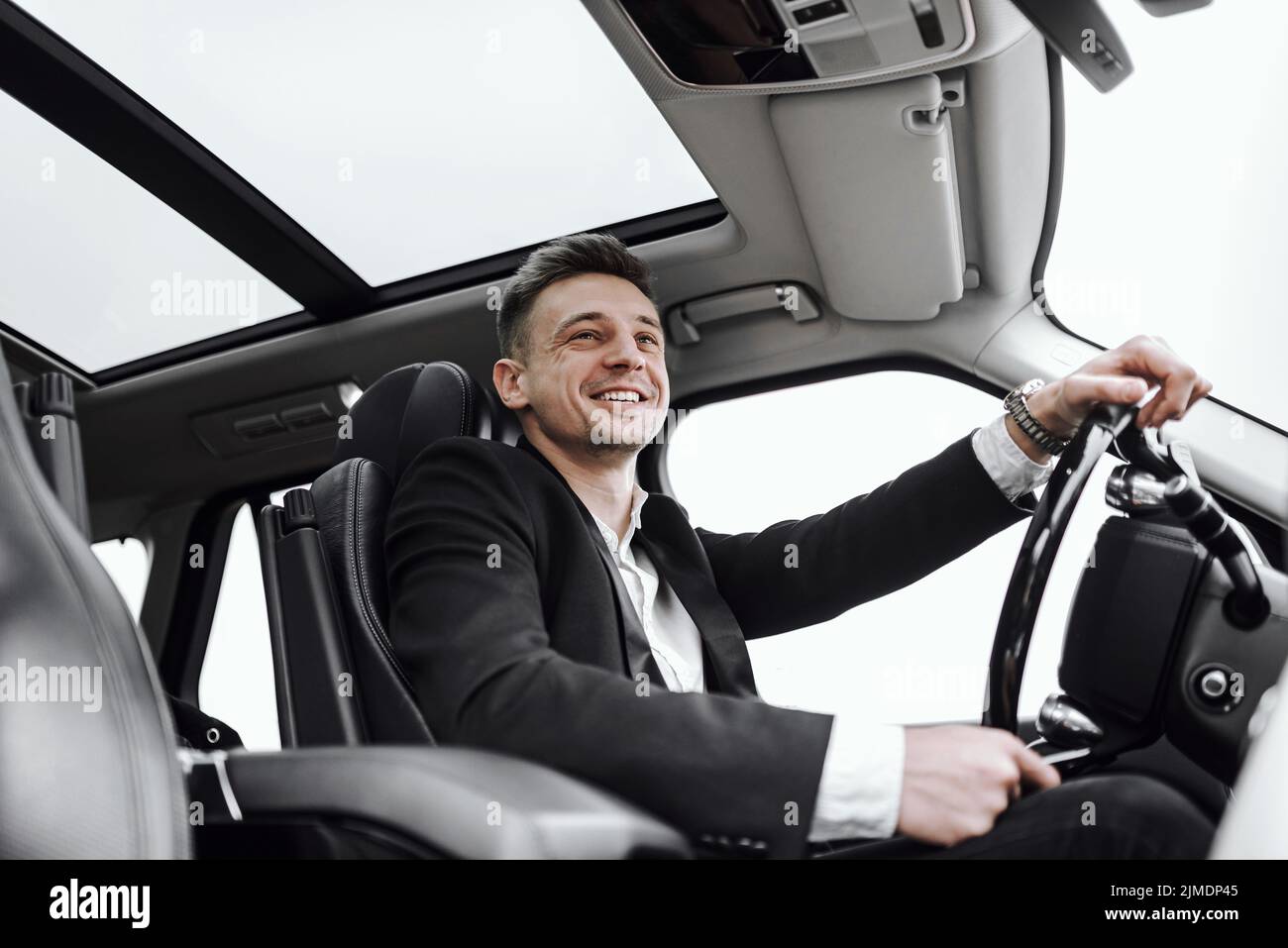 Lächelnder, gutaussehender junger Mann fährt Auto Stockfoto