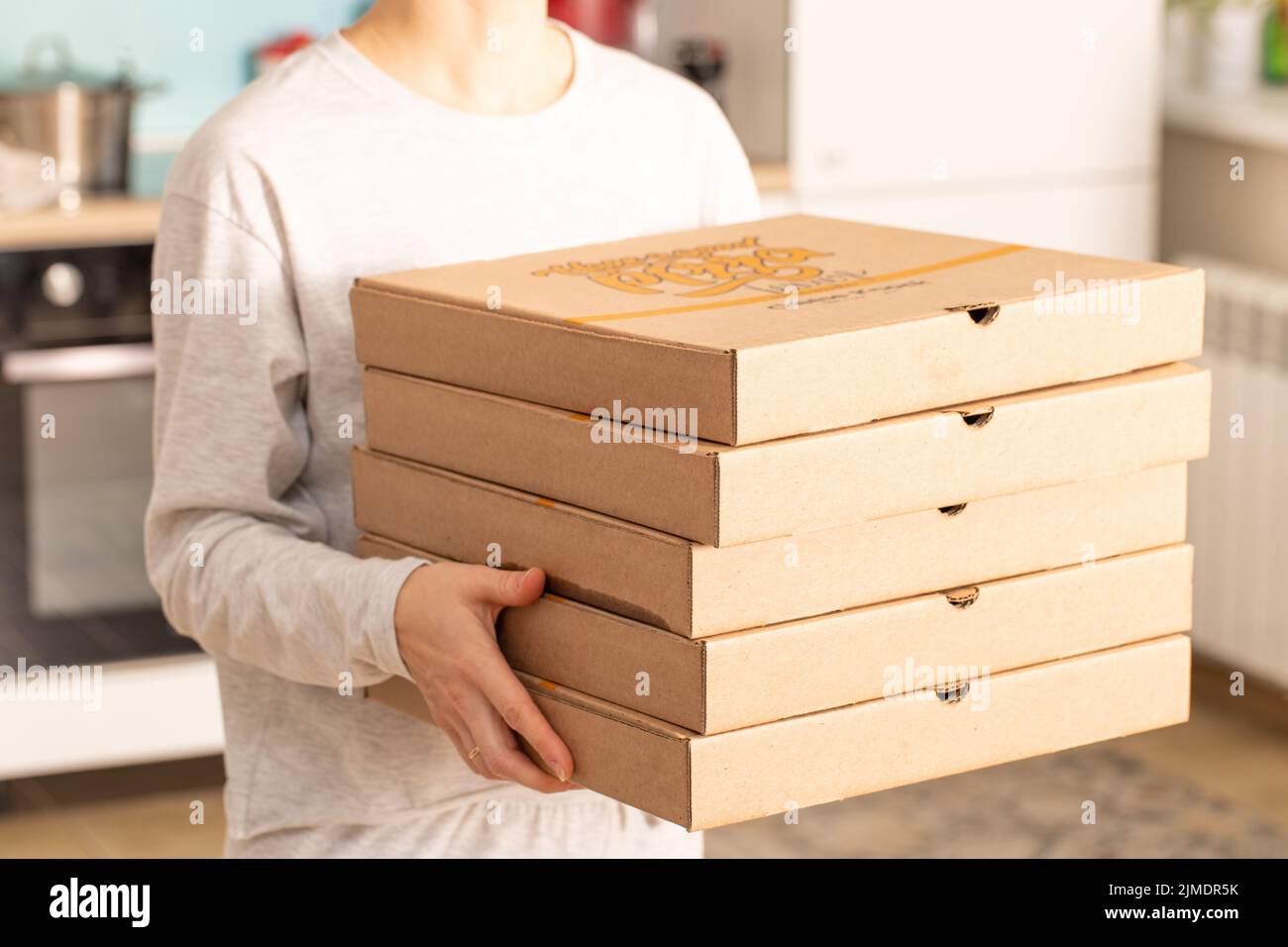 Nach Hause liefern Lebensmittel. Mädchen hält Bestellung für Pizza oder Kuchen auf verschwommenem Hintergrund in zu Hause Stockfoto