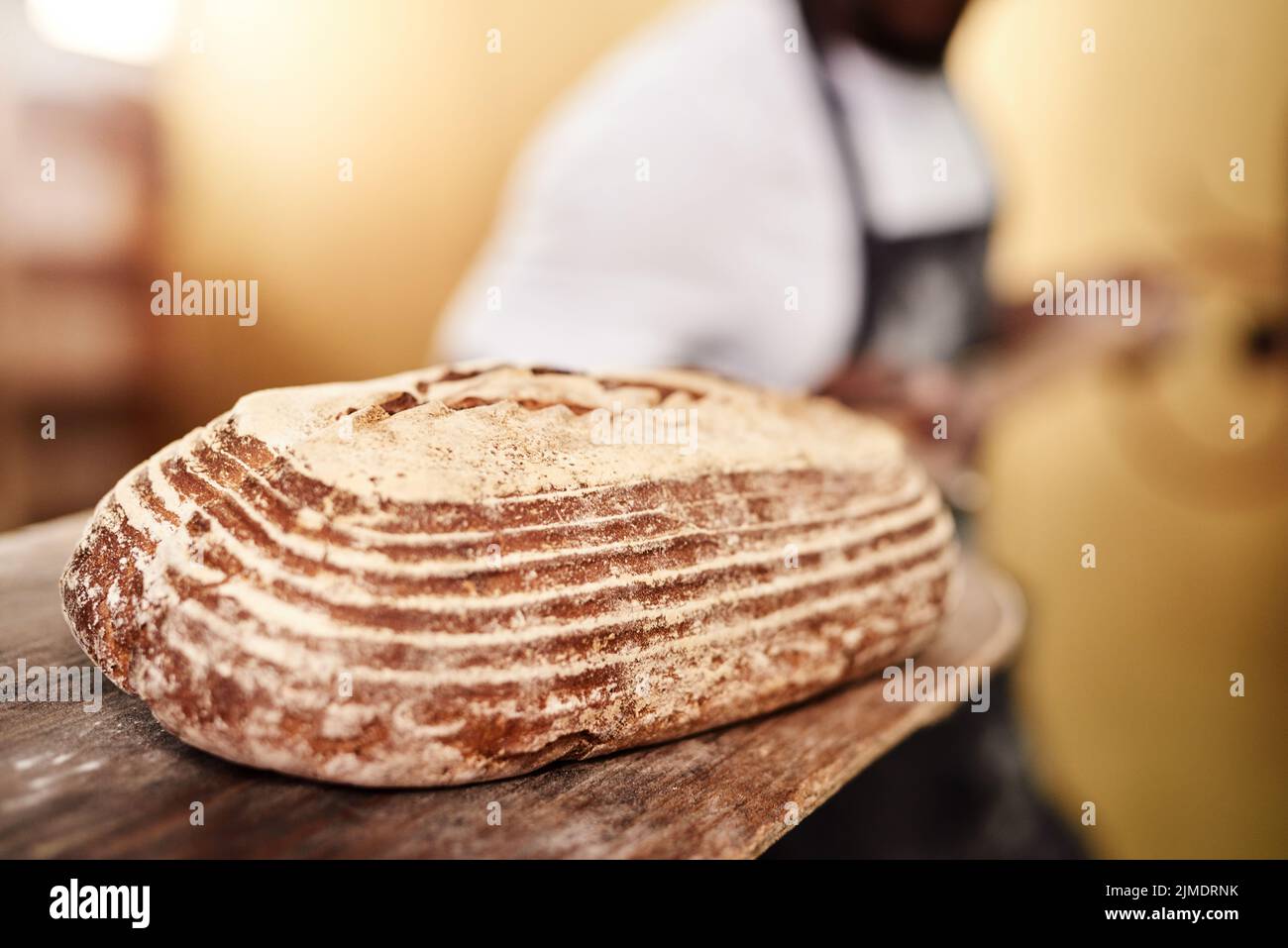 Es ist das Beste in der Stadt. Ein männlicher Bäcker, der frisch gebackenes Brot aus dem Ofen herausgenommen hat. Stockfoto