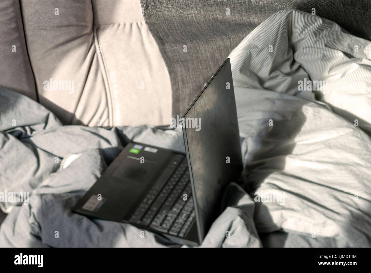 Ein Laptop in einem unordentlichen Bett mit zerknittert Bettgedecken innen Nahaufnahme Stockfoto