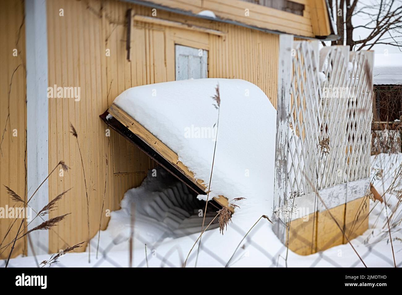 Winterlandschaft mit teilweise beschädigtem Holzhaus, flacher Freiheitsgrad Stockfoto