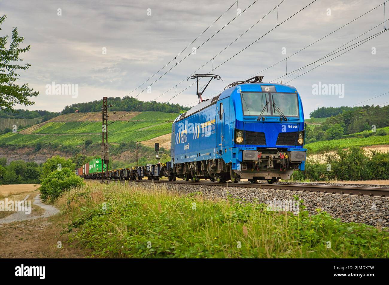 Der Blick auf eine blaue Lokomotive auf den Eisenbahnen unter dem wolkigen Himmel Stockfoto