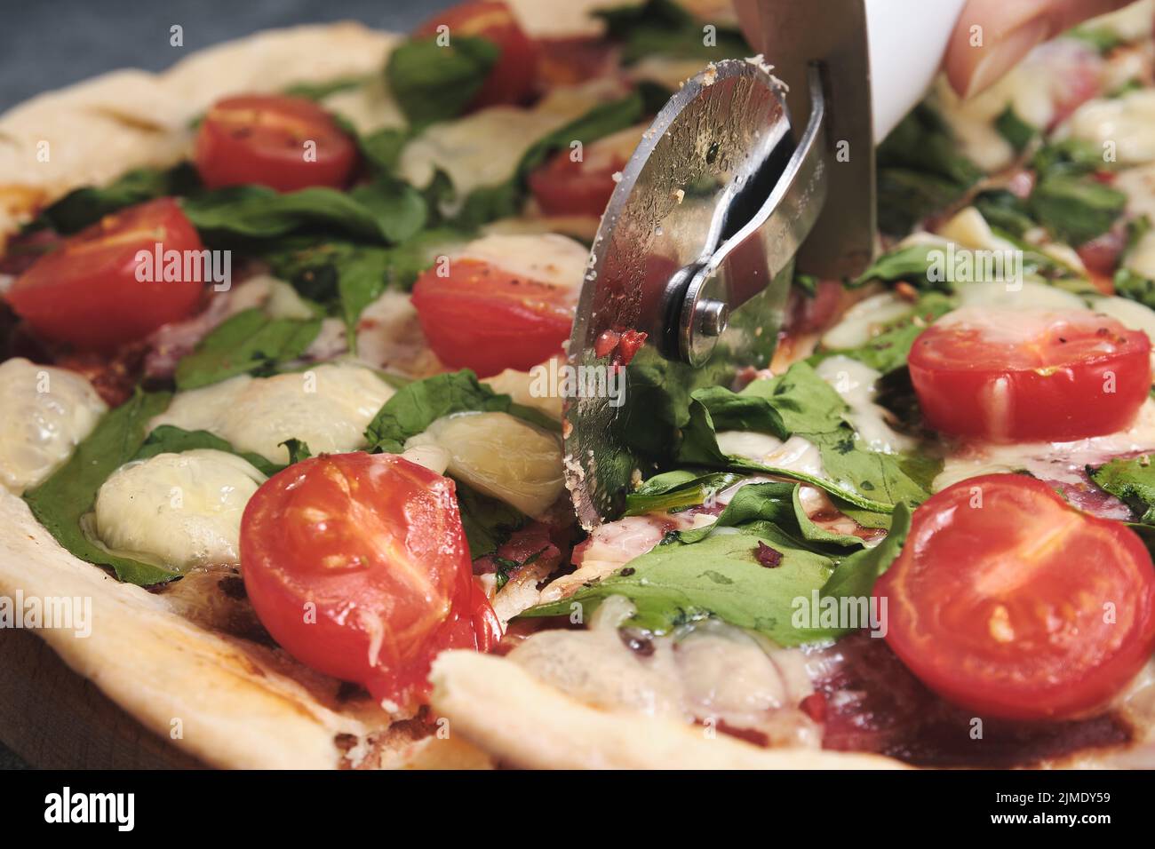 Pizza mit Käse, Tomaten, Spinat und Räucherwurst Stockfoto