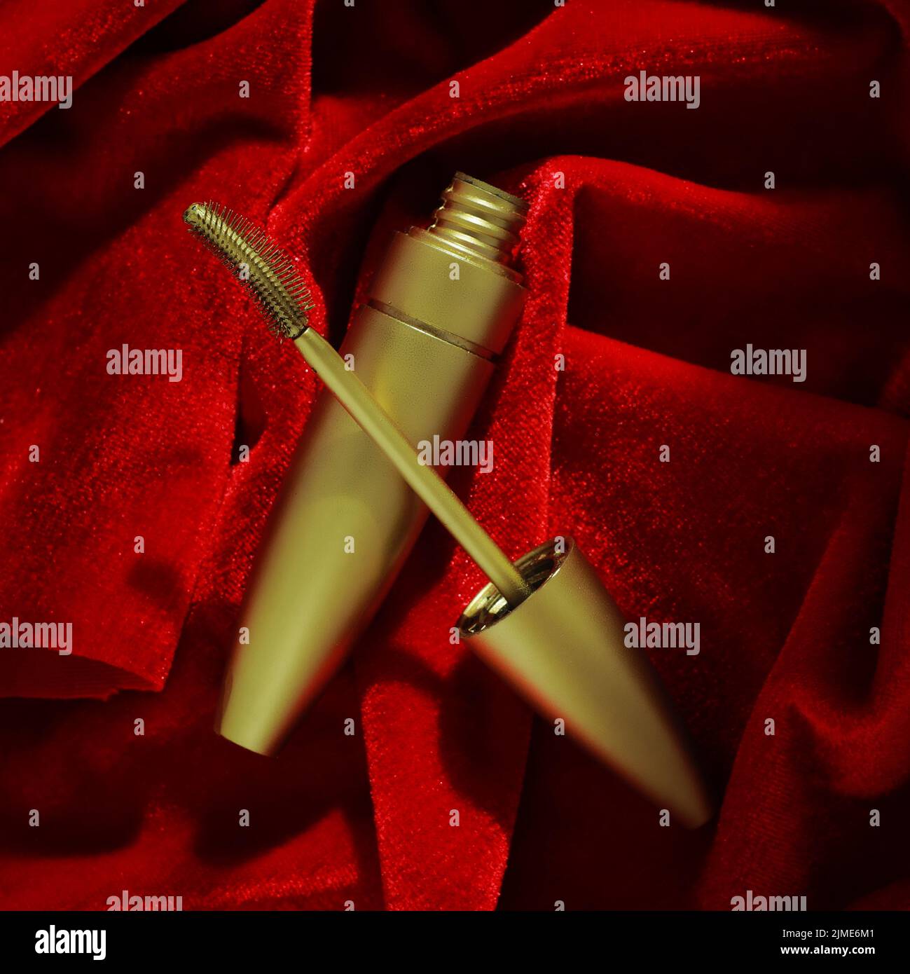 Goldene Mascara auf rotem Samt. Werbefoto von Kosmetik. Draufsicht Stockfoto