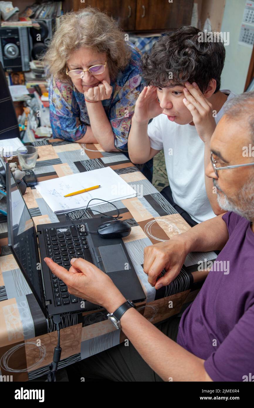 Enkel, der von seinen Großeltern unterrichtet wird, amüsiert sich vor dem Laptop zu Hause Stockfoto