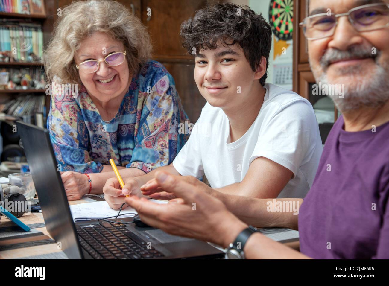 Großeltern und Teenage Boy zu Hause versammelten sich lächelnd um Laptop Stockfoto