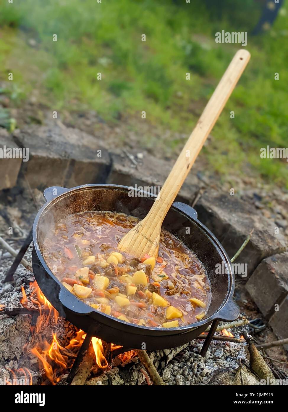 Gourmet-Rindereintopf, der in einem Kessel auf der Feuerstelle im Freien zubereitet wird Stockfoto