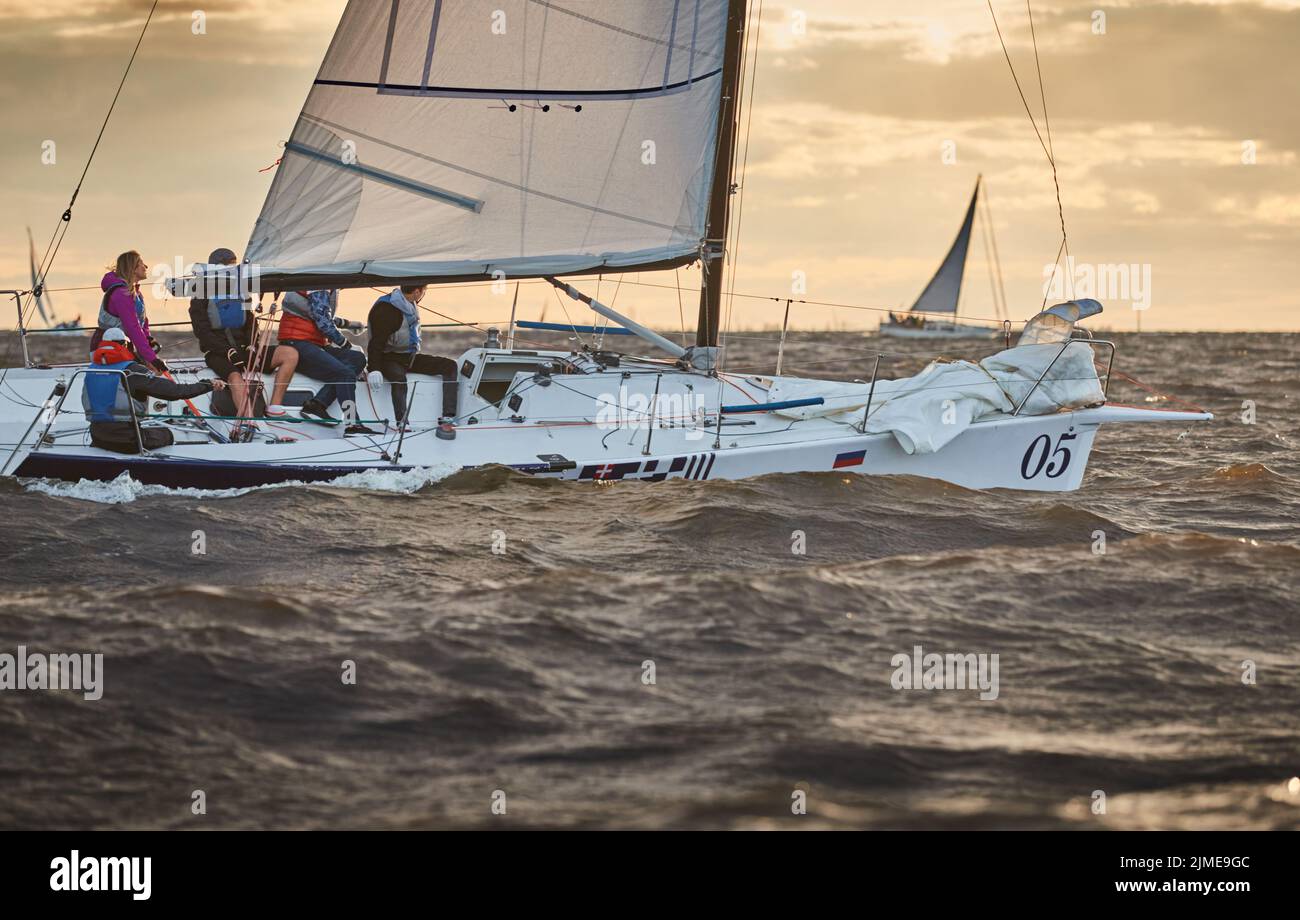 Wettbewerb von zwei Segelbooten am Horizont im Meer bei Sonnenuntergang, der erstaunliche Sturmhimmel in verschiedenen Farben, Rennen, große Wellen, Segel r Stockfoto