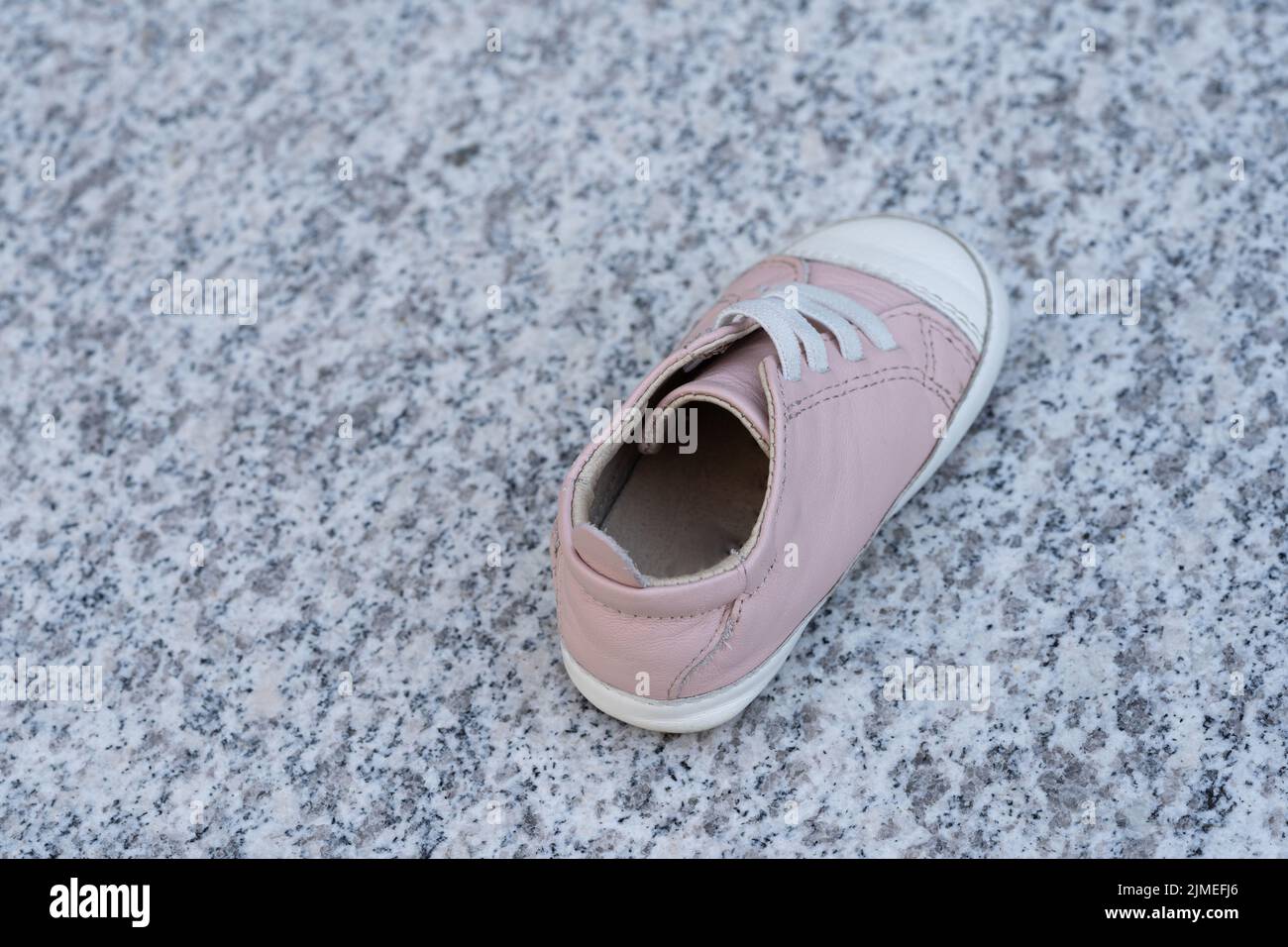 Ein rosa Babyschuh auf einem Marmorhintergrund. Einfach von jemandem verloren oder des Kindesmissbrauchs oder der Entführung verdächtigt Stockfoto