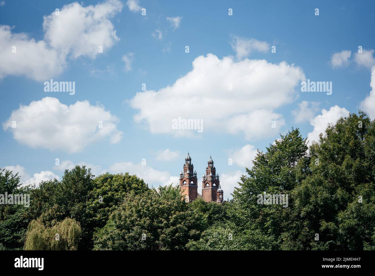 Blick auf grüne Bäume vor blauem Himmel mit weißen Wolken im Kelvingrove Park zum Kelvingrove Museum in Glasgow, Schottland Stockfoto