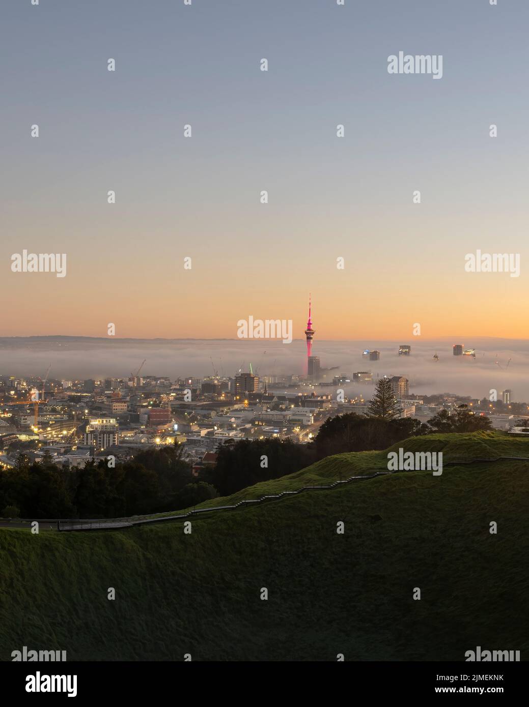 Sky Tower in Pink und Auckland City im Nebelmeer, vom Mount Eden Summit. Vertikales Format. Stockfoto