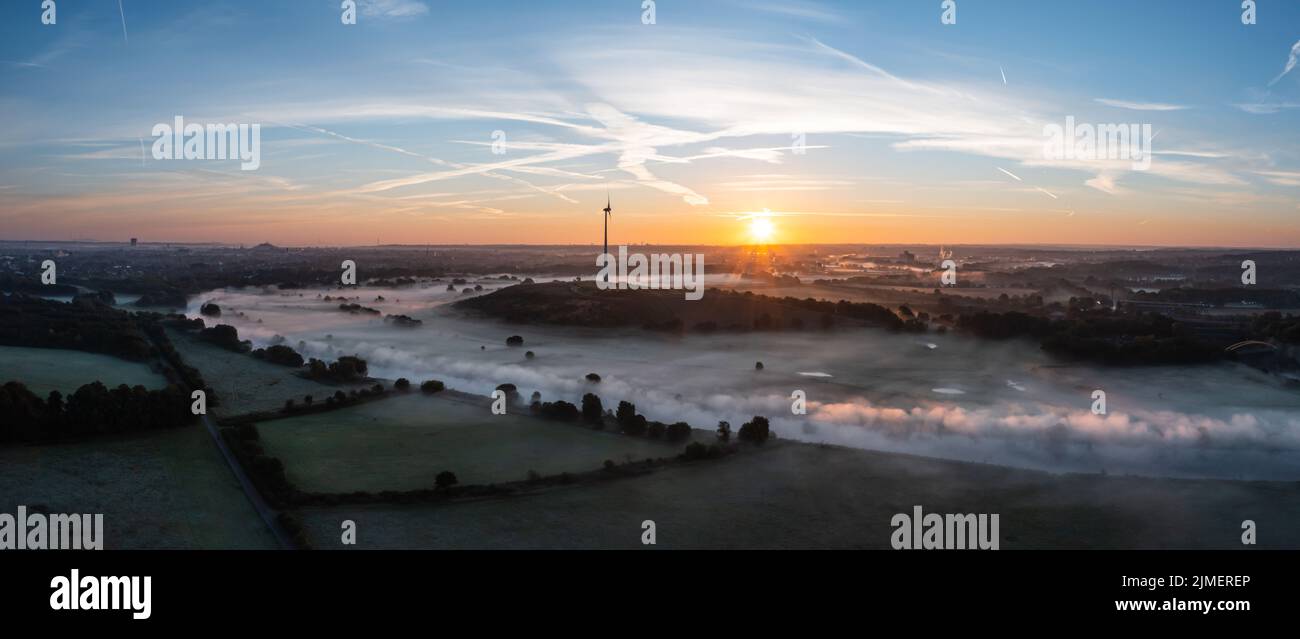 Sonnenaufgang und die ersten Sonnenstrahlen über den nebelbedeckten Ruhrwiesen in Duisburg Stockfoto