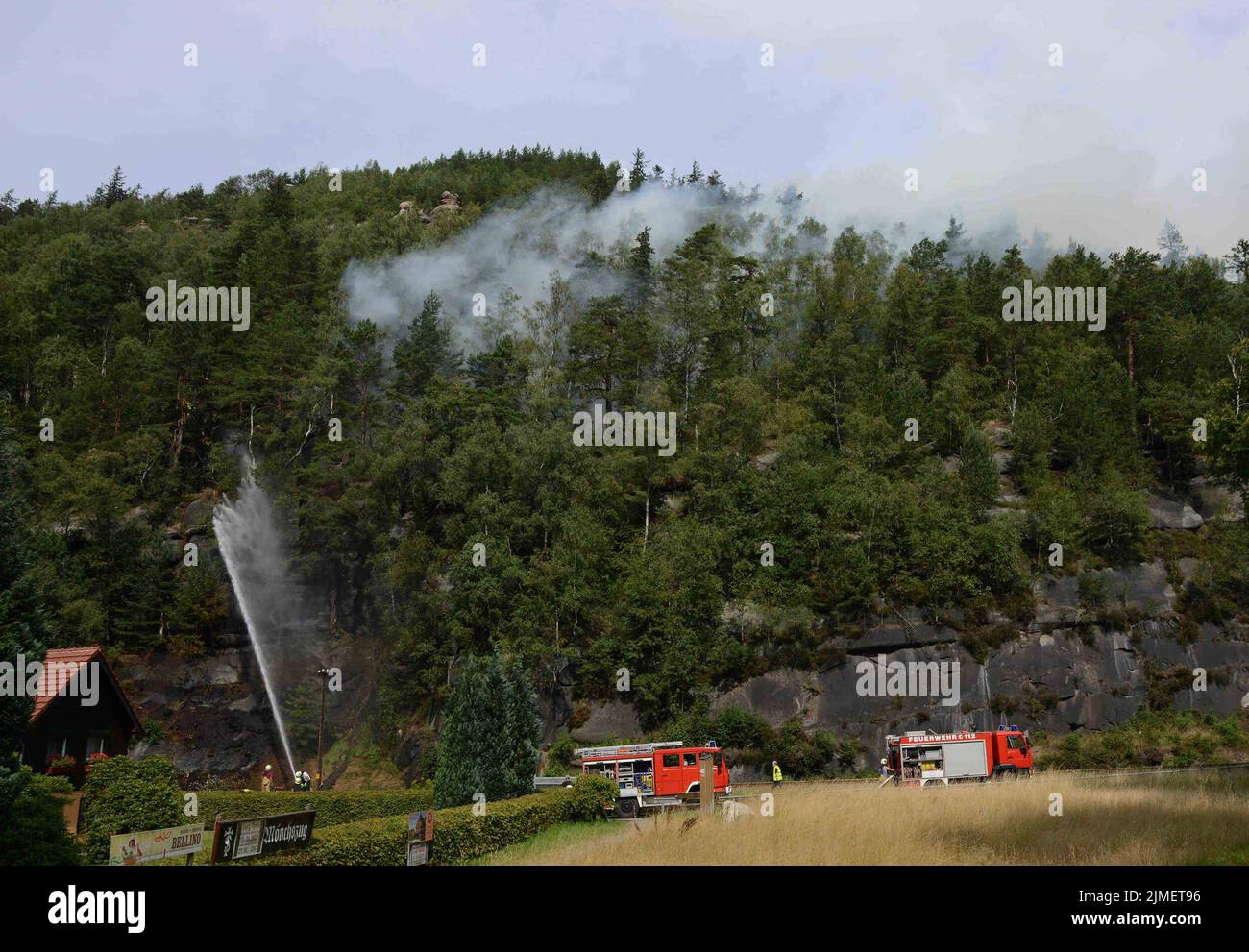 Oybin, Deutschland. 05. August 2022. Feuerwehrleute löschen einen Waldbrand aus einem Fahrzeug. In der Ortschaft im Landkreis Görlitz ist ein Waldbrand ausgebrochen. Die Feuerwehrleute können derzeit nicht an die Brandquelle gelangen. Das Gelände ist ähnlich unpassierbar und felsig wie im Nationalpark Sächsische Schweiz. Kredit: Christian Essler/Xcitedress/dpa/Alamy Live Nachrichten Stockfoto