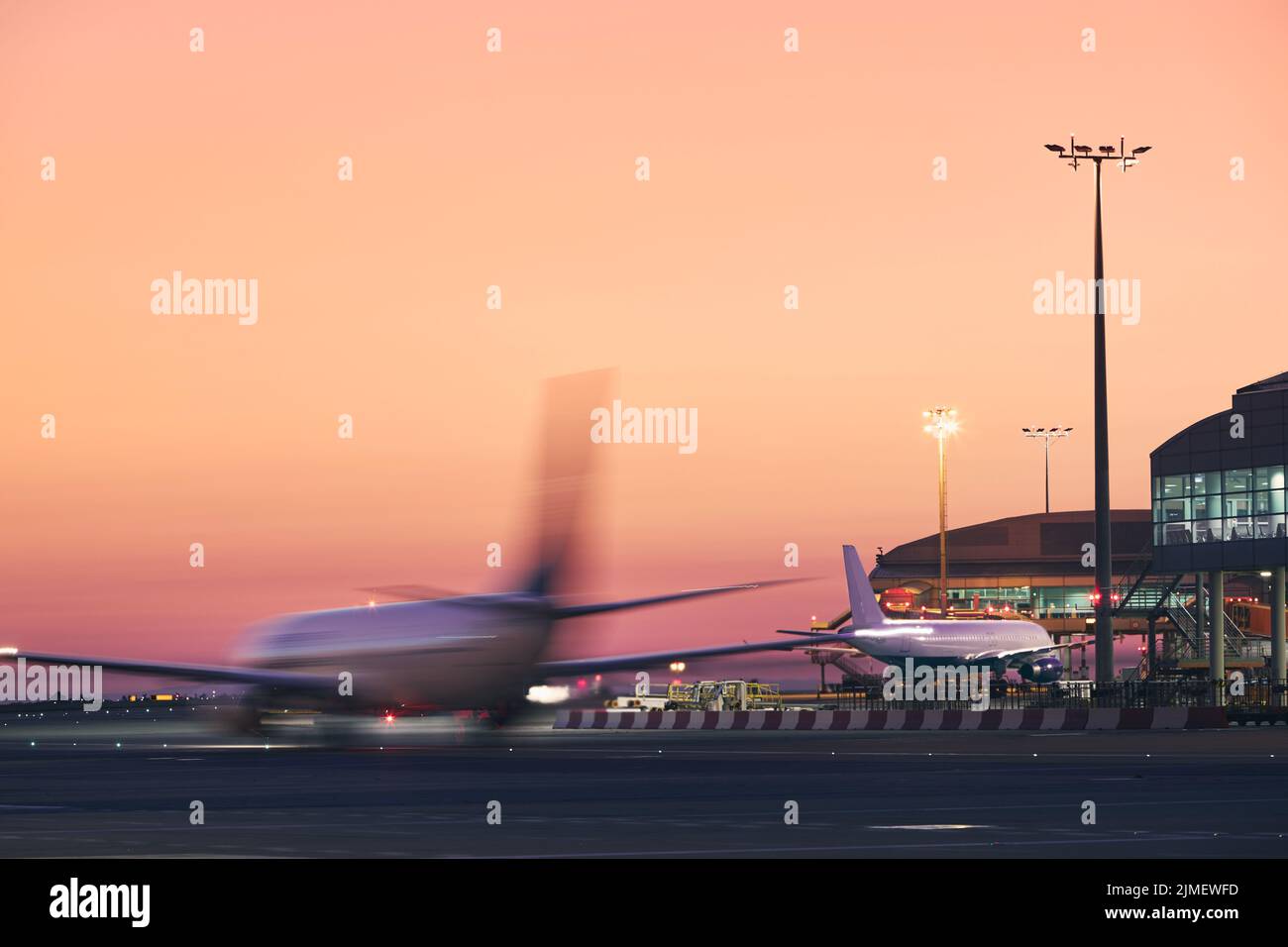 Flugzeug in unscharfer Bewegung. Verkehr am Flughafen während des farbenfrohen Sonnenaufgangs. Stockfoto