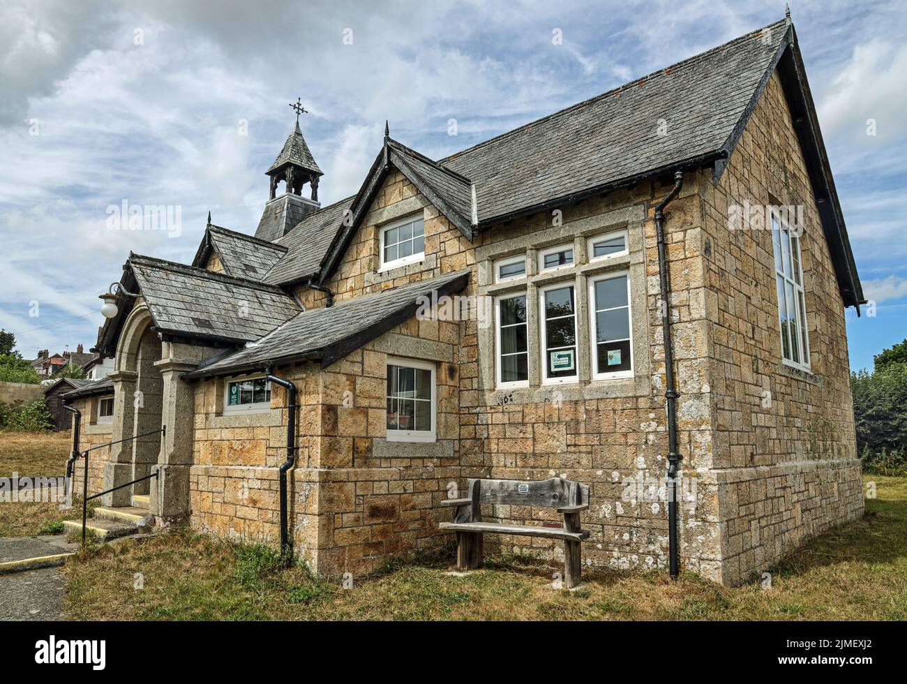 St. Andrew’s Church Hall im Dorf Little Devon von Bere Ferrers. Ein rustikaler Sitz außerhalb des malerischen Gebäudes für Passanten und die Erwähnung eines Defibri Stockfoto