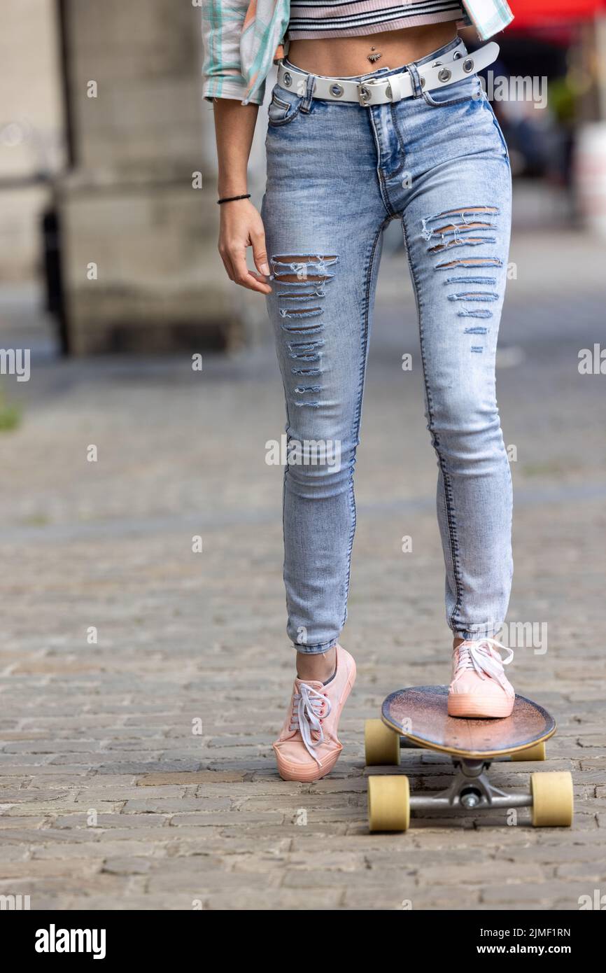 In Sneakers werden die Beine einer jungen Frau in einem kleinen Schuss mit neuen Tricks beim Skateboarden im Park geübt. Sport- und Urban-Lifestyle-Konzept Stockfoto