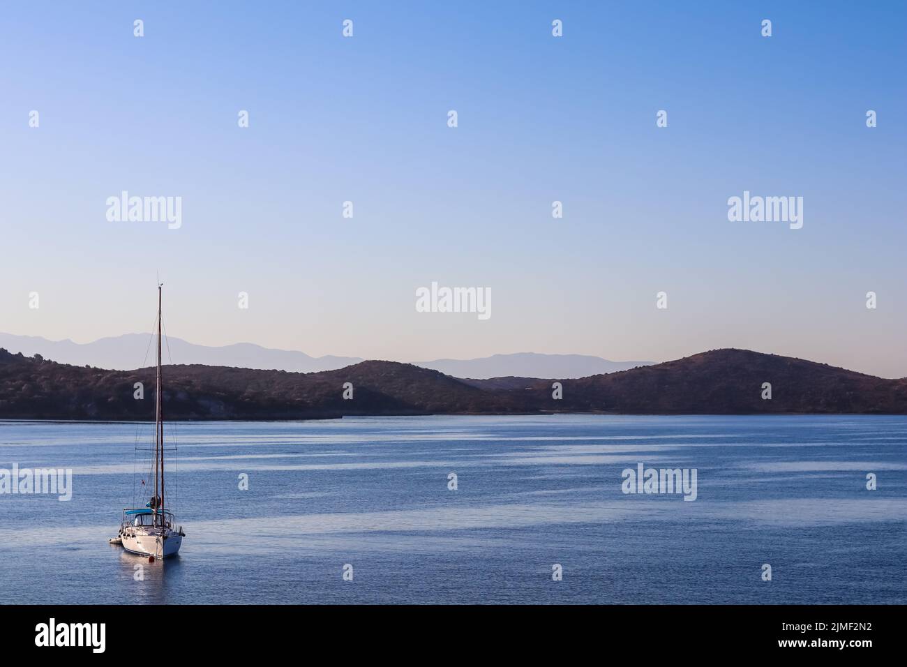 Blaues Meer, ein Boot und Berge bei Sonnenaufgang. Ruhige Meereslandschaft und Küstenlandschaft Stockfoto