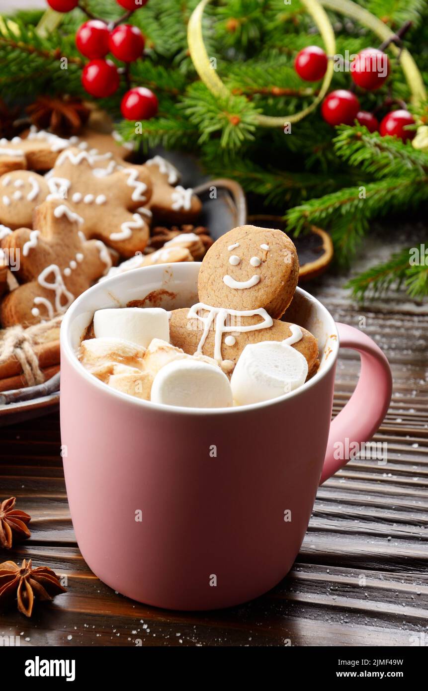 Rosa Becher mit heißer Schokolade und Marshmallows Gingerbread Man auf dem Hintergrund der Fichte Zweig und Fach mit Cookies Stockfoto