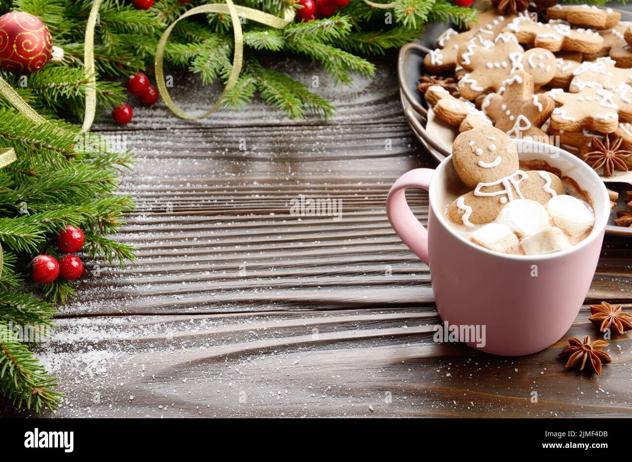 Rosa Becher mit heißer Schokolade und Marshmallows Gingerbread Man auf dem Hintergrund der Fichte Zweig und Fach mit Cookies Stockfoto
