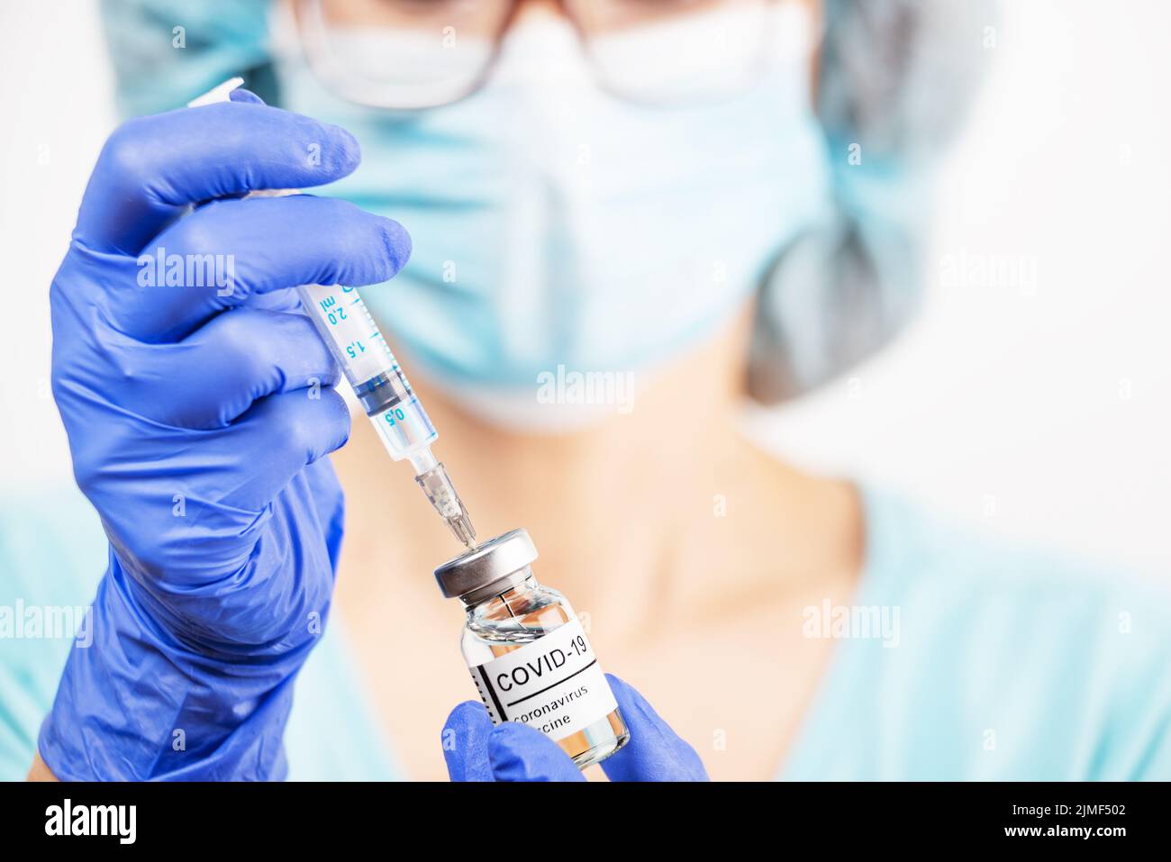 Kaukasische Ärztin mittleren Alters mit Schutzbrille und Handschuhen, die eine Spritze für die Injektion des Coronavirus-Impfstoffs vorbereitet Stockfoto