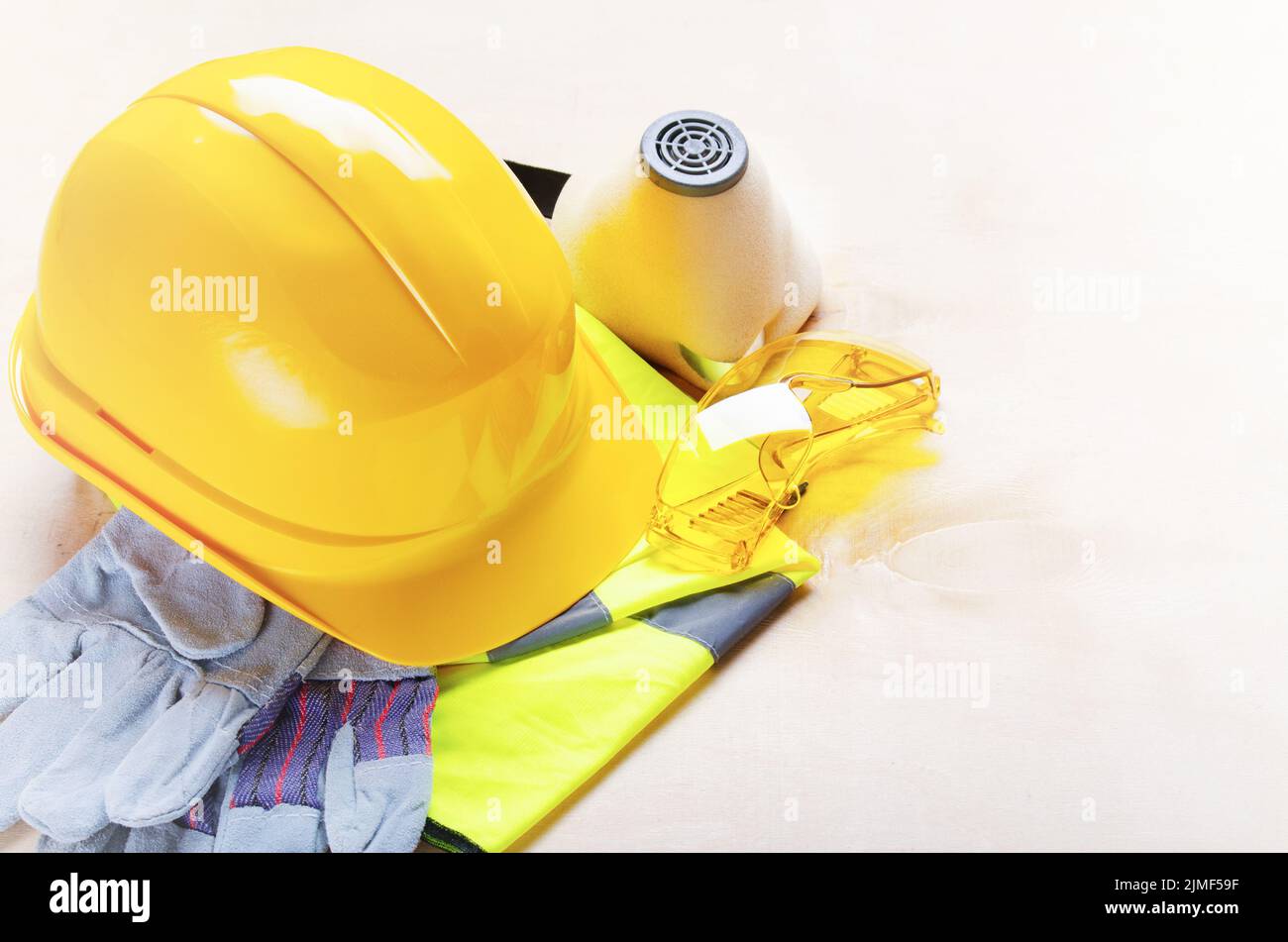 Gelber Plastikmütze, Brille, Atemschutzmaske, reflektierende Weste und Schutzhandschuhe auf Sperrholz. Sicheres Arbeitskonzept Stockfoto