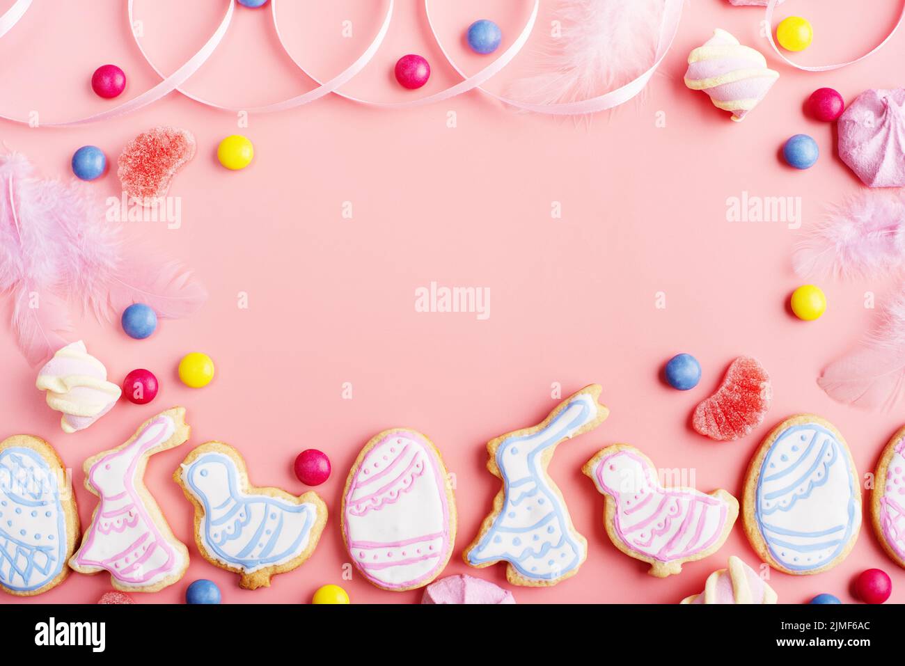 Bonbons und Osterklätzchen in Form von Hühnchen und Kaninchen auf rosa Hintergrund. Flaches Lay-Mockup mit Kopierplatz. Stockfoto