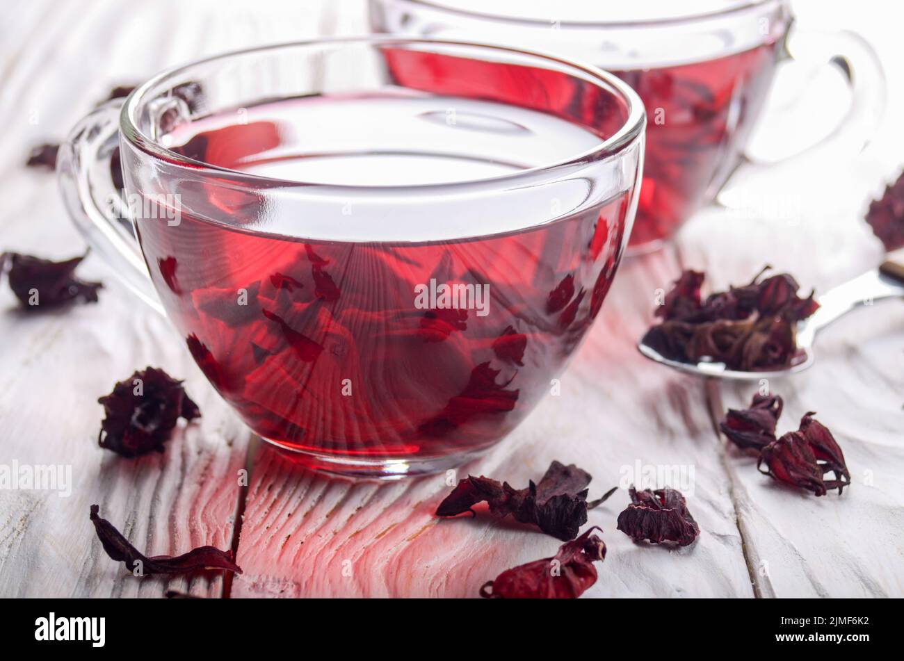 Detailansicht an zwei Teetassen und trockenen Hibiscus Blüten auf Weiß Holztisch Hintergrund Stockfoto