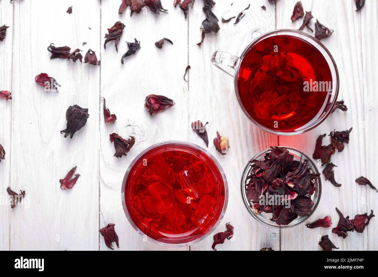 Draufsicht bei zwei Tassen mit Eis und trockenen Hibiscus Blüten auf Weiß Holztisch Hintergrund Stockfoto