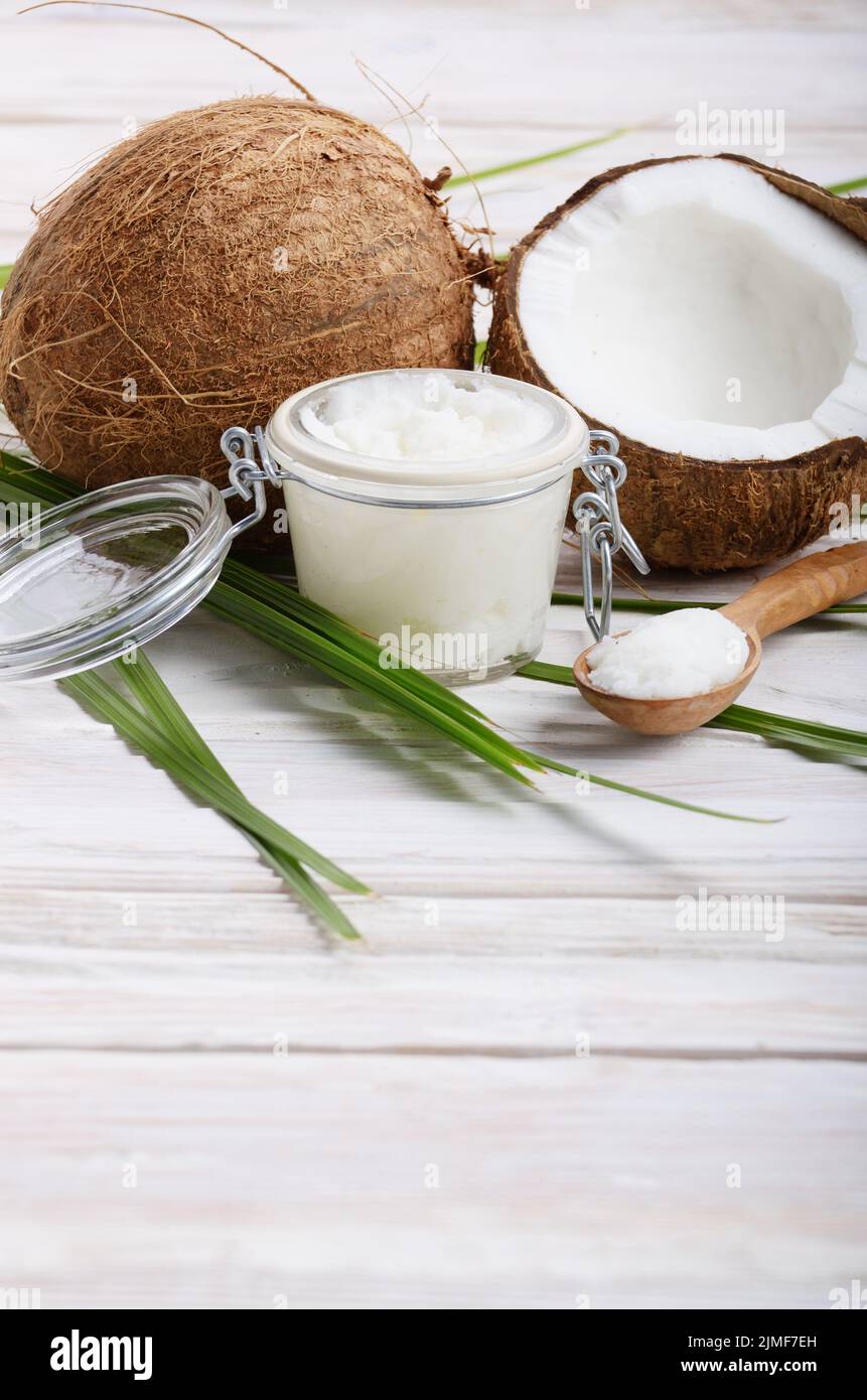 Kokosöl in luftdichten Glas, Löffel und Shell Stücke auf weiße Holztisch Stockfoto
