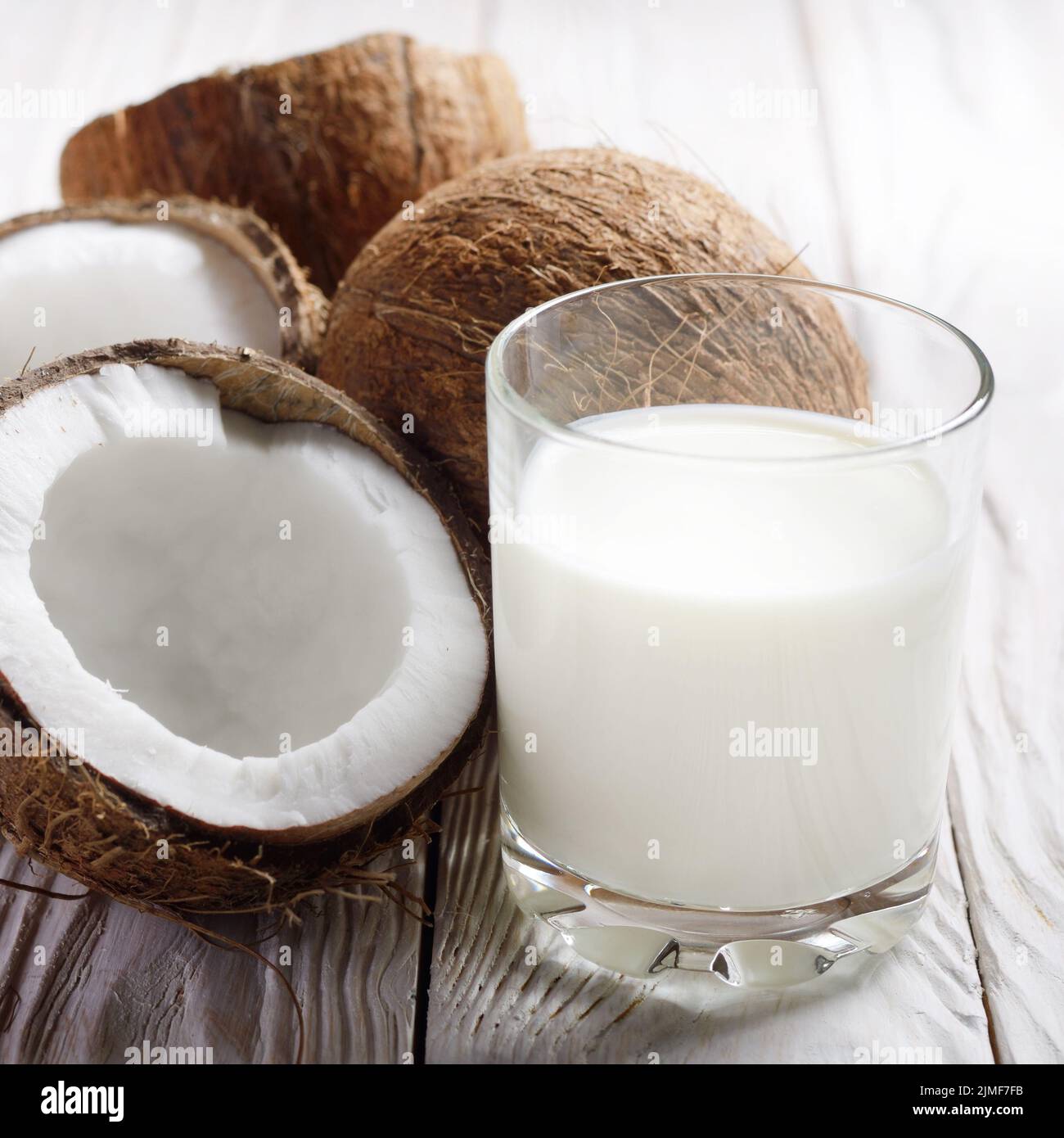 Trinken ein Glas Milch oder Joghurt auf blau serviette auf weiße Holztisch mit Kokosnuss beiseite Stockfoto