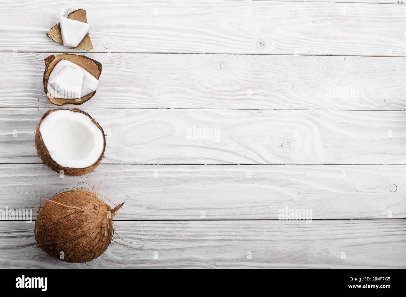 Flach Hintergrund der Kokosnuss, Kokosnussschalen und Fleischstücke auf weissem Holztisch Stockfoto