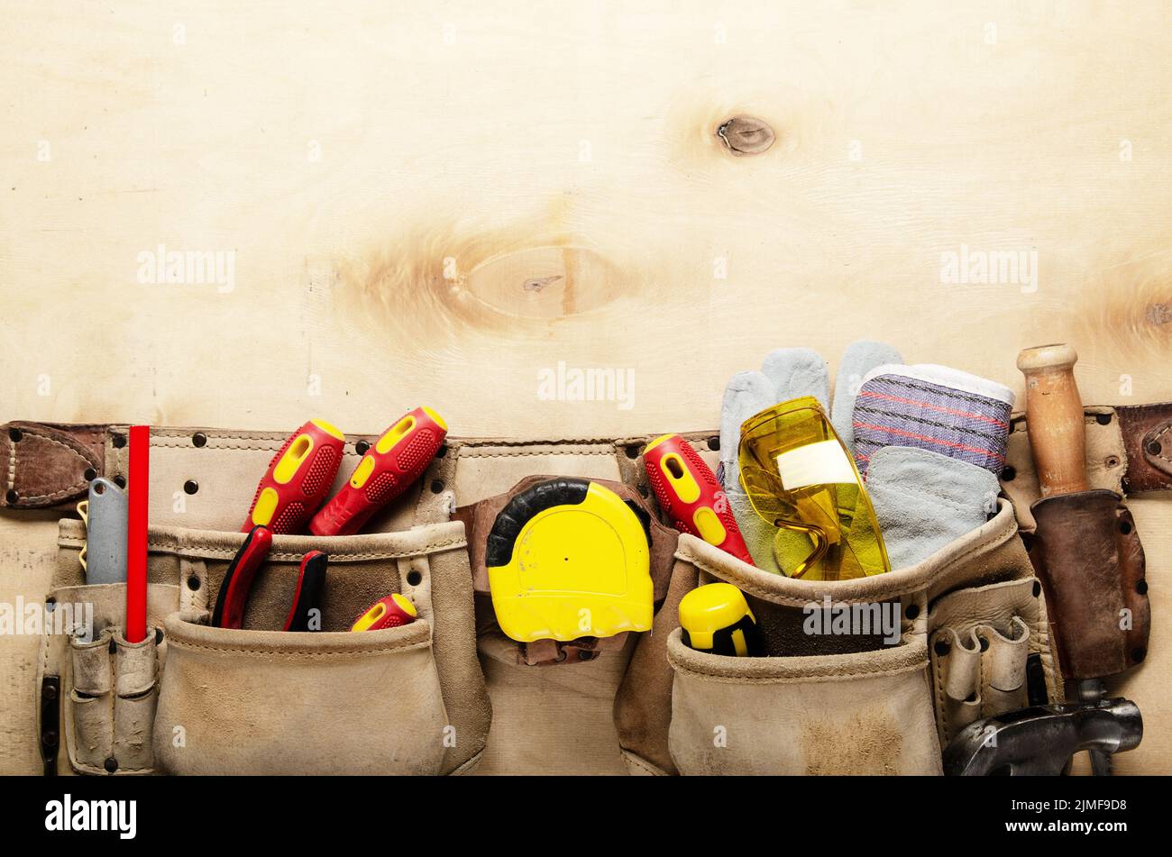 Werkzeuggürtel mit Tischlerwerkzeugen und Schutzverschleiß auf Sperrholz Flachblattansicht des Blatts Stockfoto