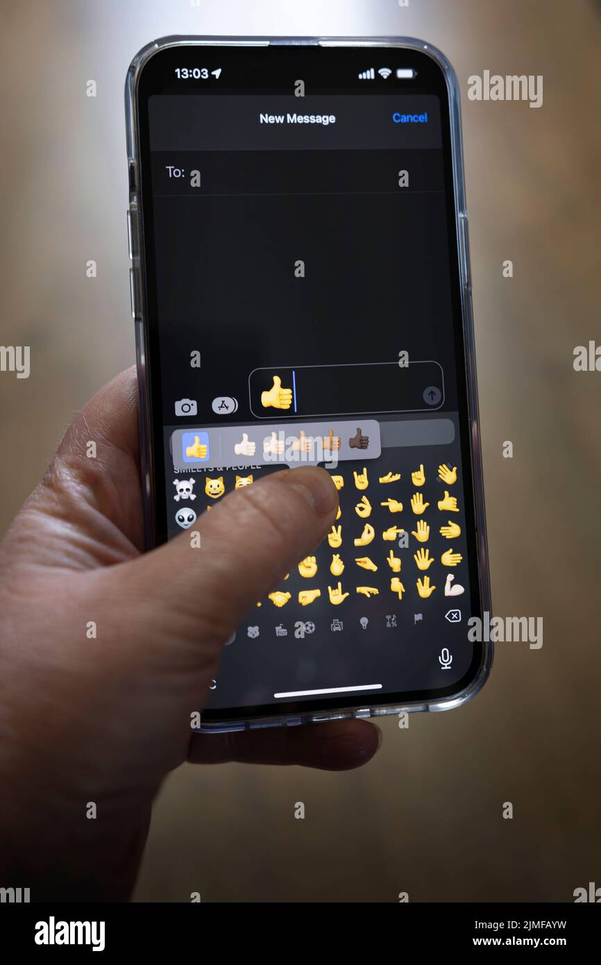 Das iPhone 13 pro max wird mit einer kaukasischen Hand gehalten, die einen Vater antwortet, Daumen nach oben Emoji Stockfoto