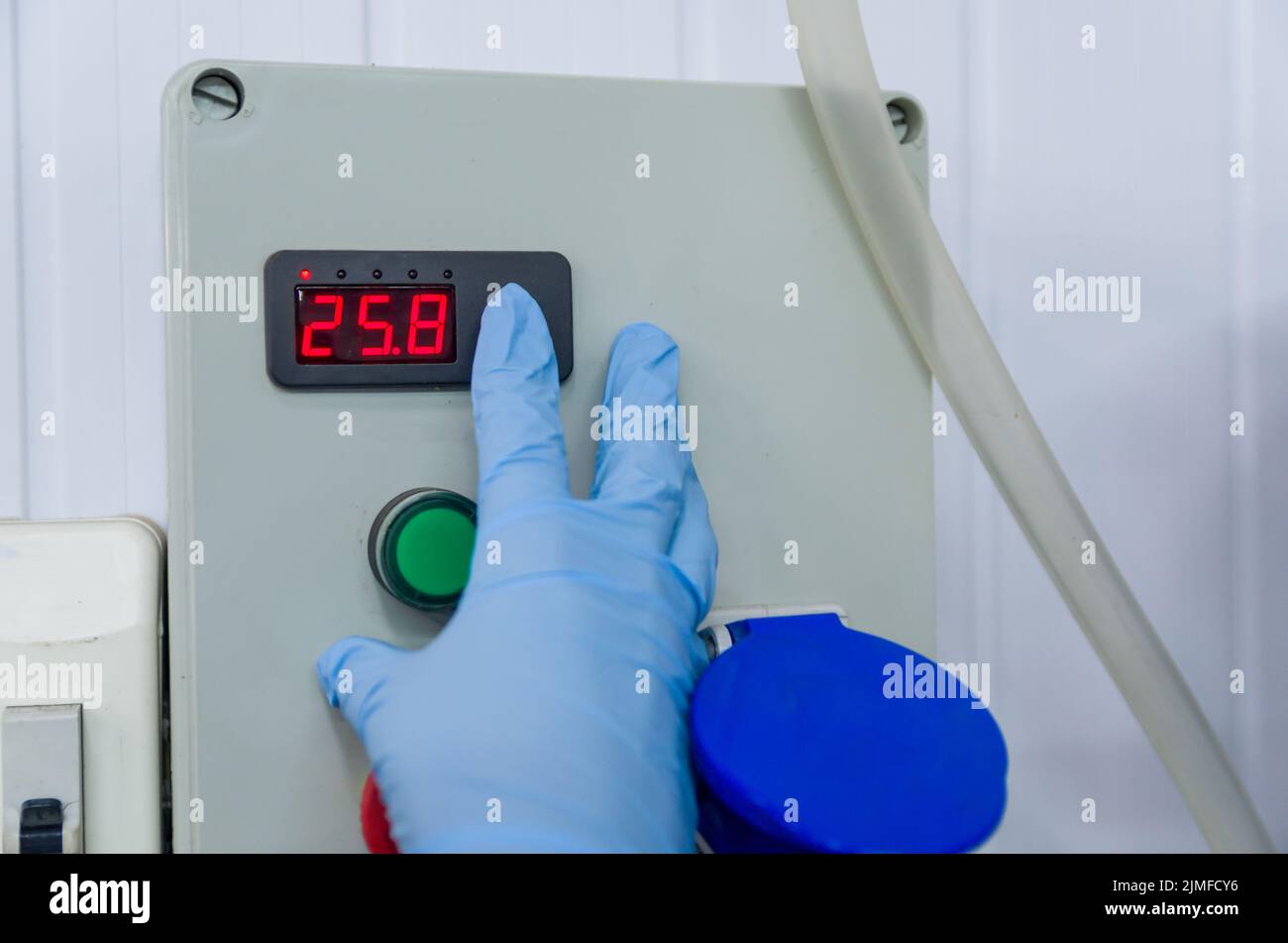 Frau, die in der Industrie arbeitet und den Tankthermostat justiert Stockfoto
