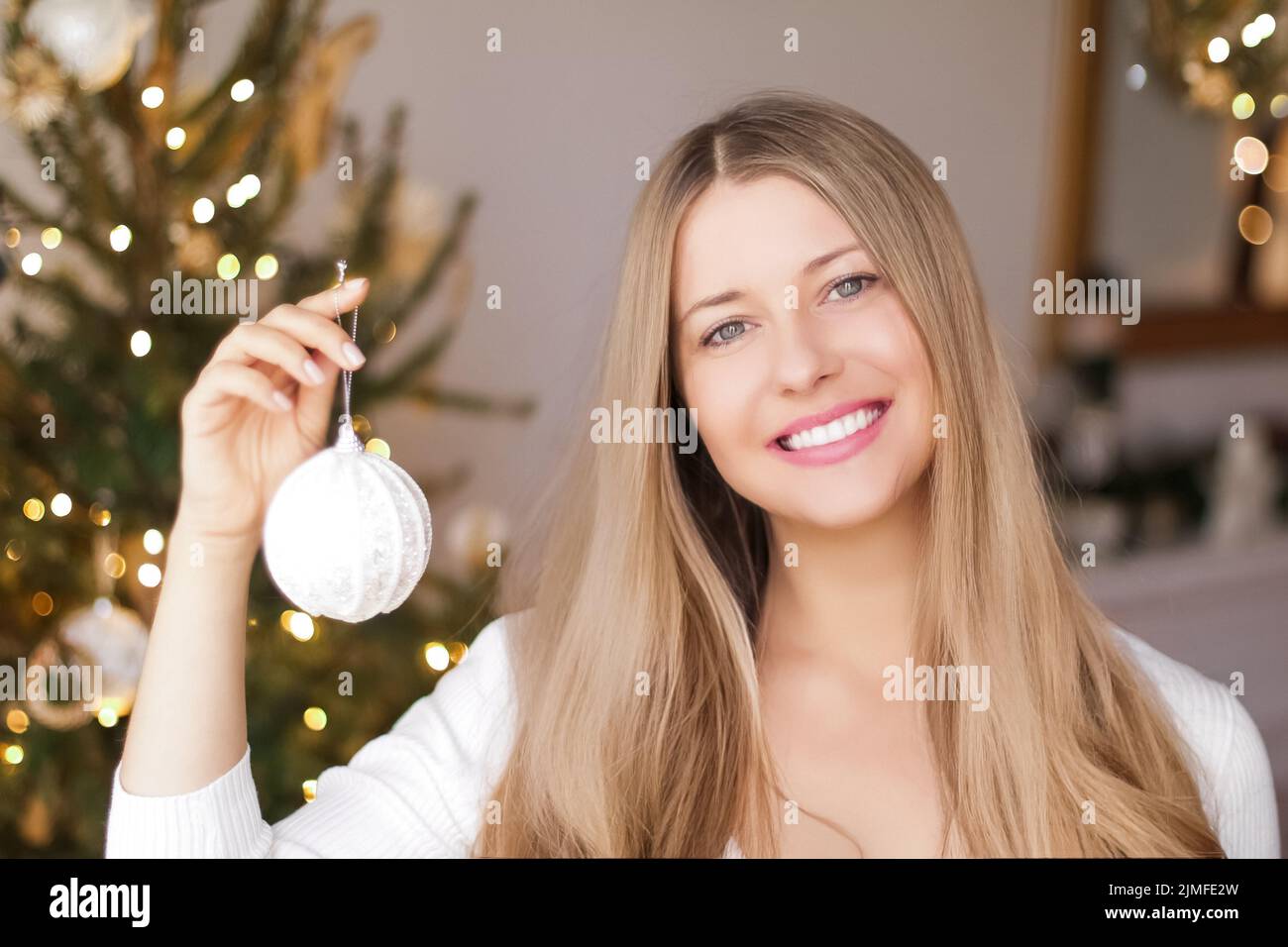 Dekoration Weihnachtsbaum und Winterferien Konzept. Glücklich lächelnde Frau hält festliche Ornament zu Hause Stockfoto