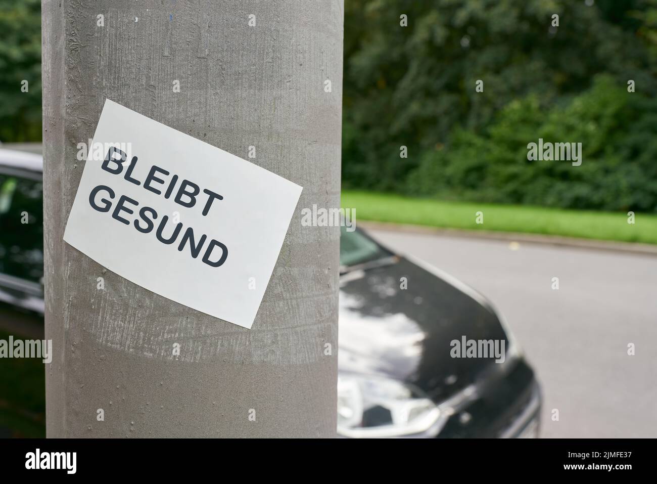 Aufkleber auf einer Säule in der Berliner Innenstadt während der Pandemie. Übersetzung: Gesund bleiben Stockfoto