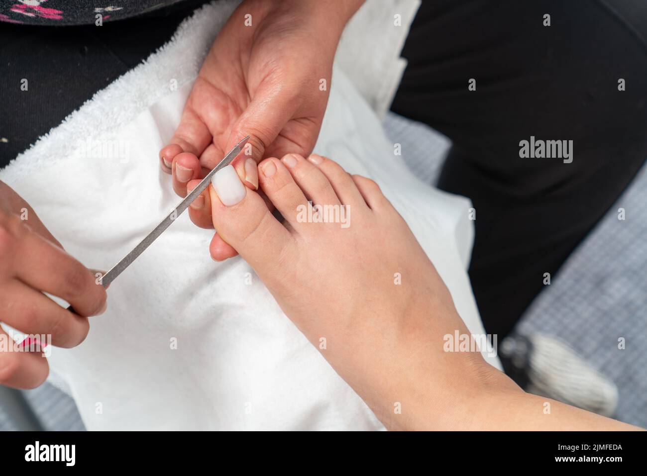 Nahaufnahme des Zehennagelfeilens. Frau erhalten professionelle Pediküre Behandlung im Schönheitssalon. Beauty und kosmetisches Konzept. Hochwertige Fotos Stockfoto