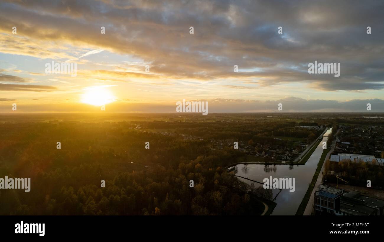 Schöner Sonnenuntergang über einem Fluss mit grünen Büschen und farbigem Himmel Stockfoto