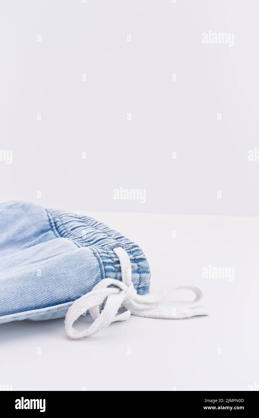 Jeans-Jogginghose mit Coulisse auf einem weißen Schreibtisch mit Platz für Text Stockfoto