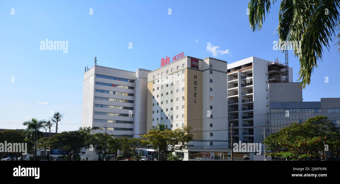 Fassade eines großen internationalen Hotels, in einer Stadt im Inneren von Brasilien, Südamerika, Vordergrund, Bäume, blauer Himmel im Hintergrund Stockfoto