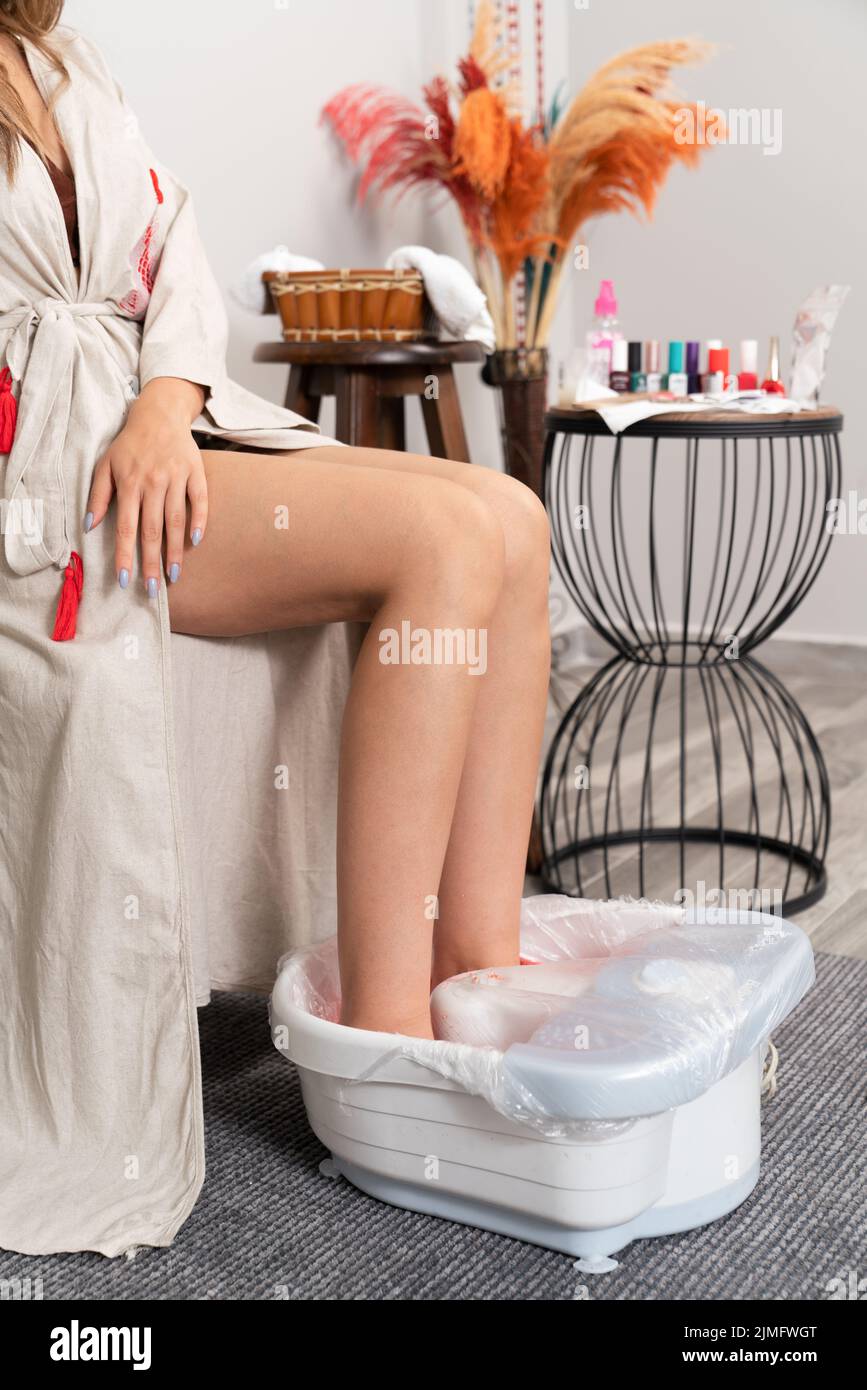 Nahaufnahme einer Frau, die ihre Füße in einer weißen Schale mit Wasser saoking, um eine Pediküre-Behandlung zu erhalten. Hochwertige Fotos Stockfoto