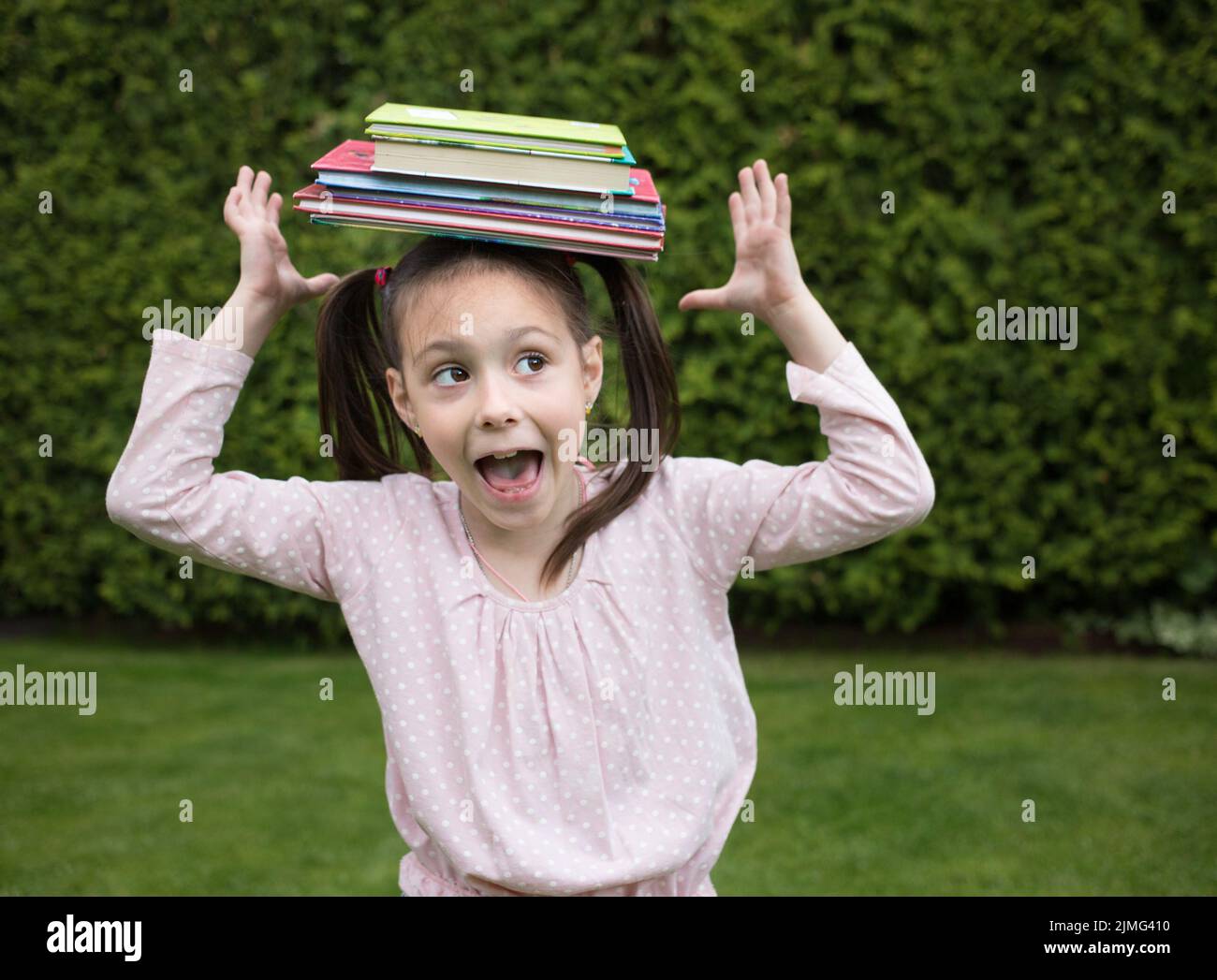 Stapel von Büchern balanciert auf dem Kopf eines 7-jährigen Mädchens, oops fällt. Zurück zur Schule Konzept. Der Sommer ist vorbei und die Schule beginnt. WLAN lesen Stockfoto