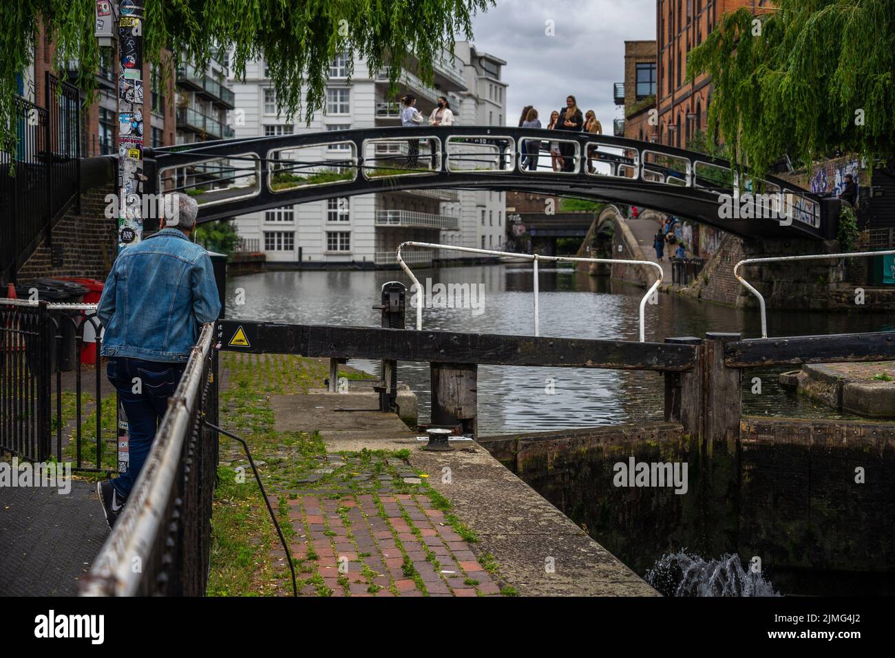 London, Großbritannien - Jun 09 2022: Älterer Mann, der an der Schiene stand, während er eine Brücke am Regent's Canal beobachtete; Londoner Straßenfotografie-Tapete für den Alltag Stockfoto