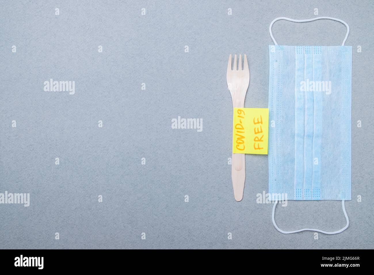 Holzgabel, blaue medizinische Maske und Aufkleber mit der Aufschrift covid-19 free. Stockfoto