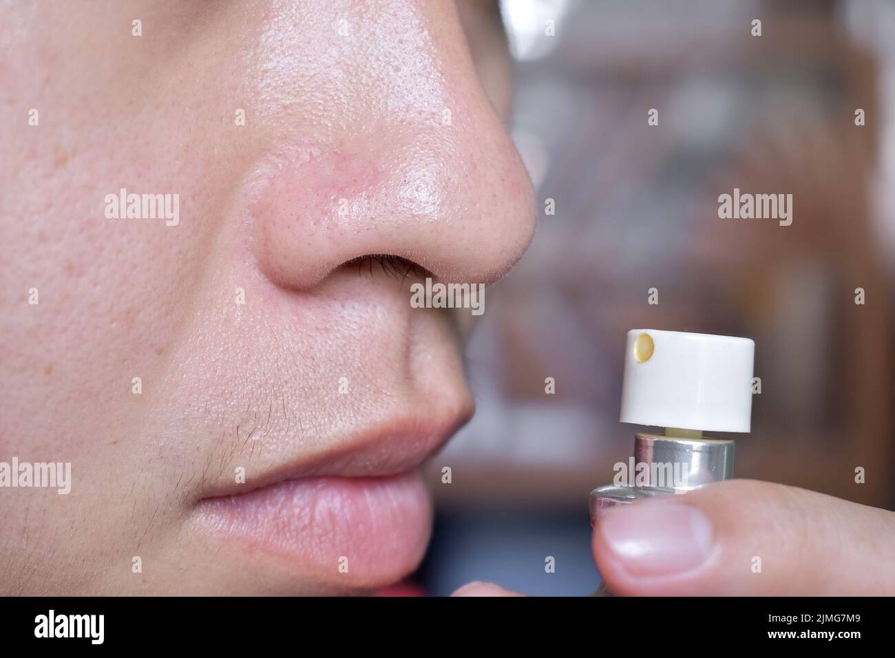 Südostasiatischer, chinesischer und myanmarischer junger Mann mit kalter Grippe bekommt Geruchverlust, genannt Anosmie. Er riecht nach Parfüm. Stockfoto