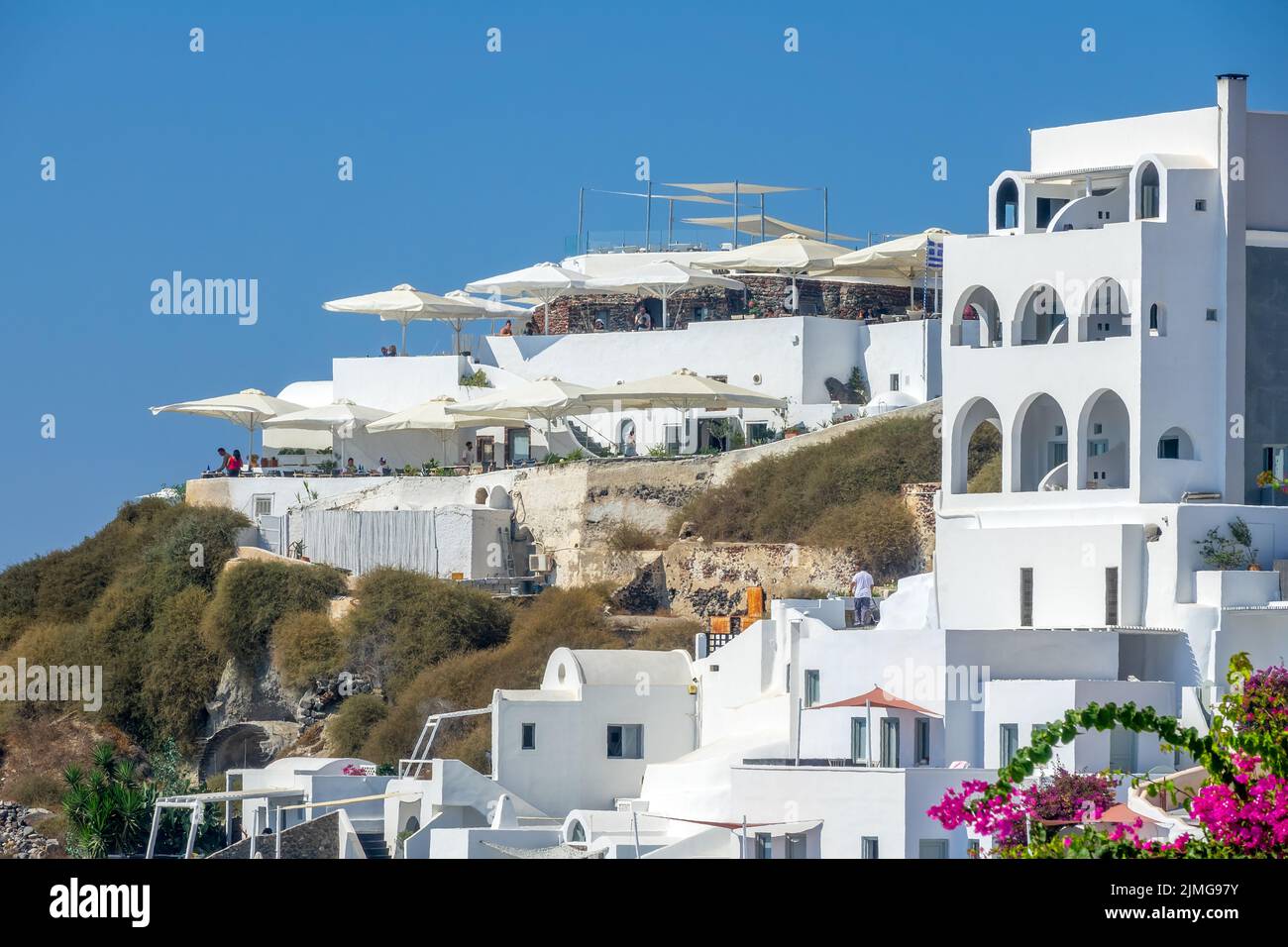 Terrassen mit Sonnenschirmen auf der Caldera von Santorin Stockfoto